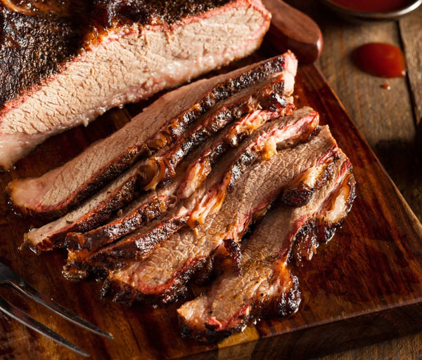 Texas Smoked Brisket on a Wooden Tablet with a Fork and BBQ Sauce